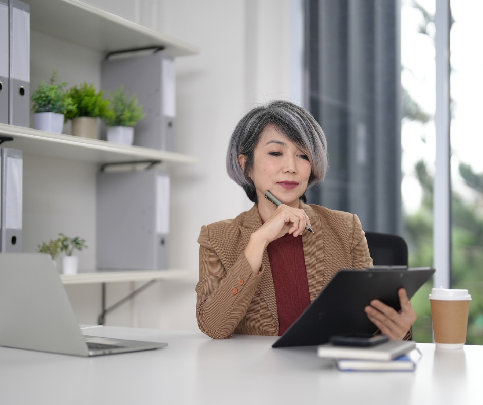 woman in her office looking at finances on a tablet and holding a pen